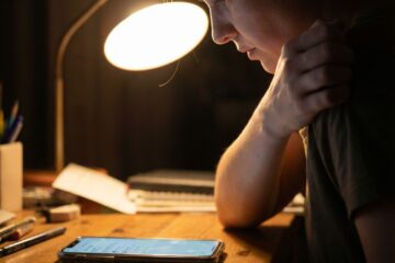 어두운 배경 속 인물이 알림에 움찔, 빛나는 스마트폰 클로즈업이다